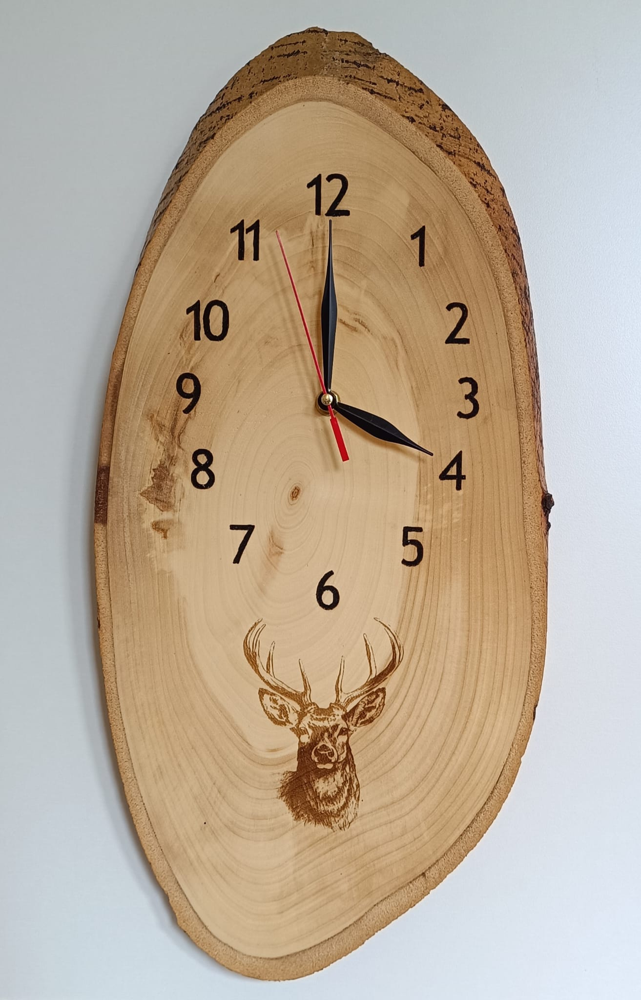 Dřevěné nástěnné hodiny "Jelen" s vygravírovaným motivem.